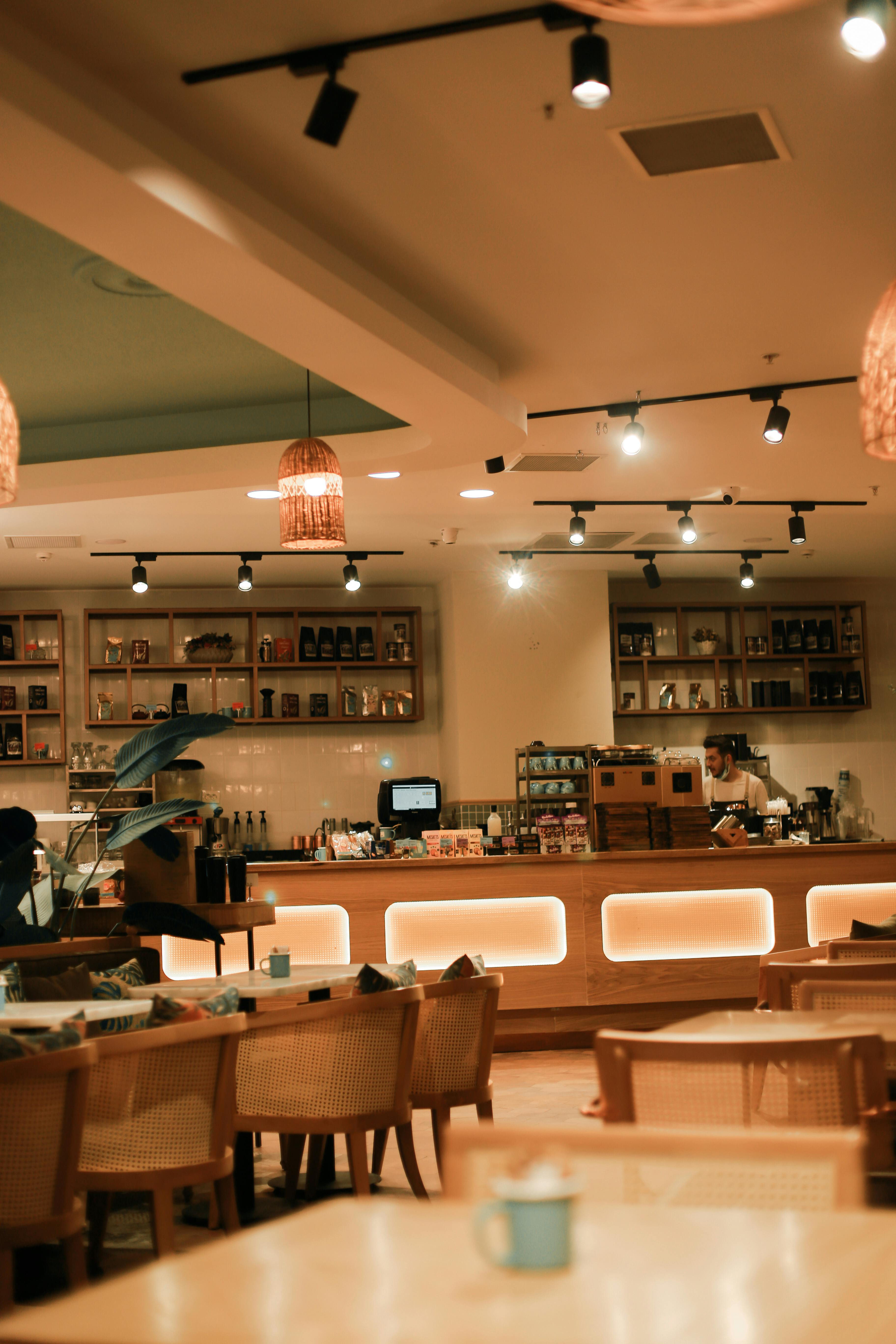Cafetería con iluminación cálida, mobiliario en madera y diseño acogedor.
